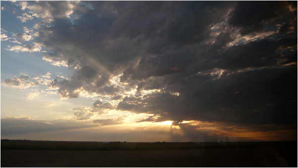 Photo of the sky with the sun peaking out from behind clouds